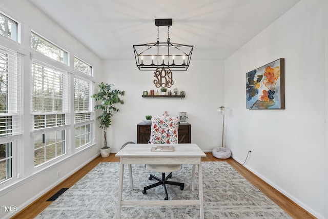 office area with a chandelier, visible vents, baseboards, and wood finished floors