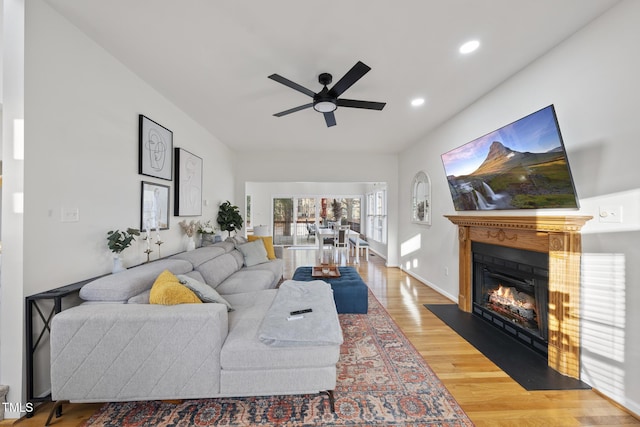 living area with a fireplace with flush hearth, a ceiling fan, wood finished floors, recessed lighting, and baseboards