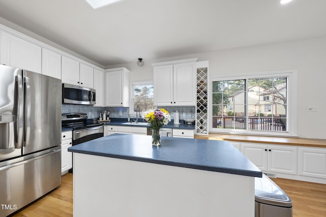 kitchen featuring light wood finished floors, dark countertops, appliances with stainless steel finishes, and white cabinetry