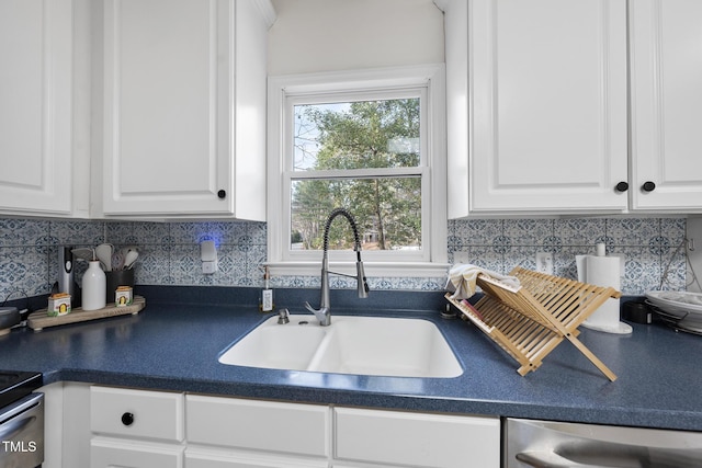 kitchen with dark countertops, white cabinets, dishwasher, and a sink