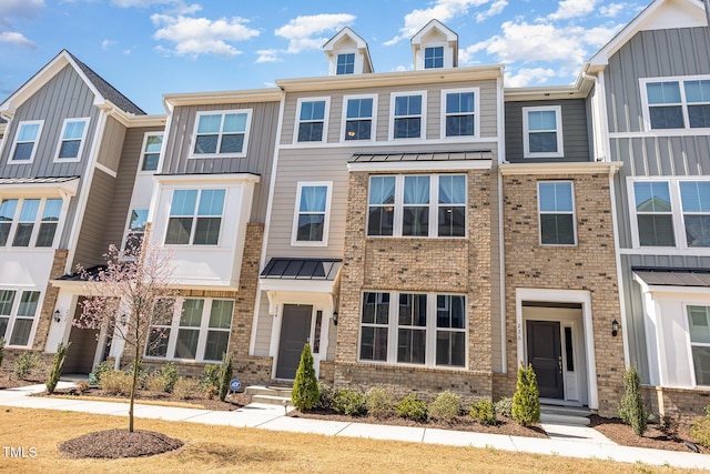 townhome / multi-family property featuring metal roof, brick siding, board and batten siding, and a standing seam roof