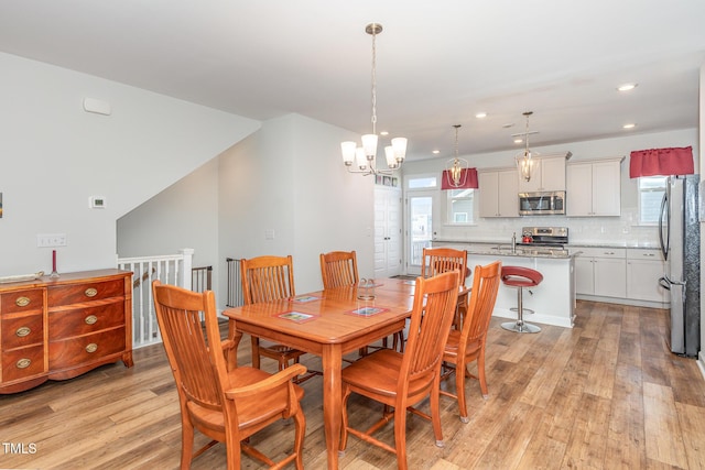 dining space with recessed lighting, a notable chandelier, and light wood-style floors