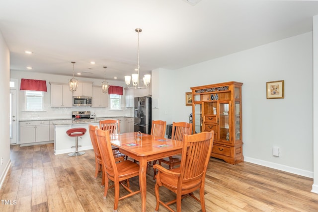 dining space featuring a notable chandelier, recessed lighting, baseboards, and light wood finished floors