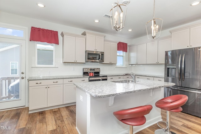 kitchen with visible vents, light wood-type flooring, a sink, appliances with stainless steel finishes, and decorative backsplash