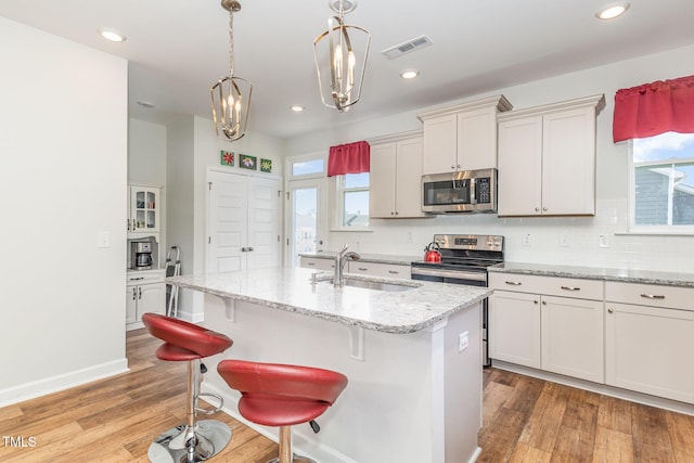 kitchen with light wood-type flooring, visible vents, a sink, tasteful backsplash, and stainless steel appliances