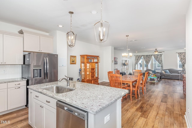 kitchen featuring a sink, tasteful backsplash, open floor plan, appliances with stainless steel finishes, and light wood finished floors