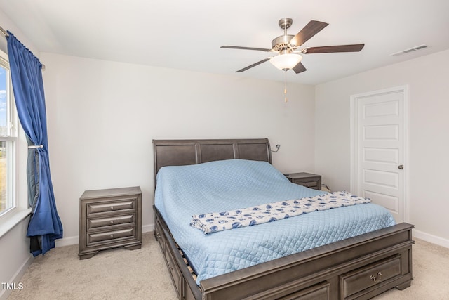 bedroom with light carpet, visible vents, a ceiling fan, and baseboards