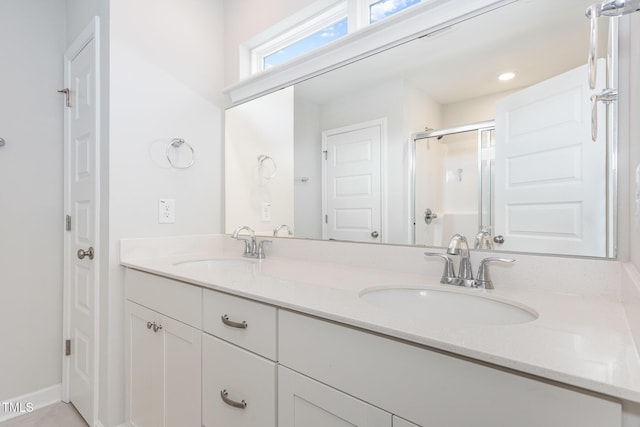 bathroom with a shower stall, double vanity, and a sink