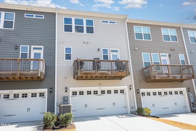 rear view of property with cooling unit, an attached garage, and driveway