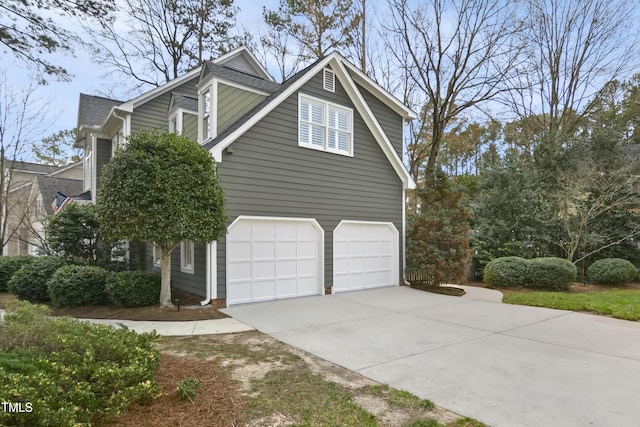 view of property exterior featuring an attached garage and concrete driveway