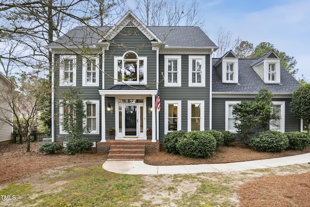 colonial house featuring roof with shingles