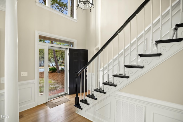 entrance foyer with a wealth of natural light, a wainscoted wall, wood finished floors, and stairs