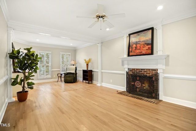 sitting room featuring wood finished floors, baseboards, decorative columns, crown molding, and a brick fireplace