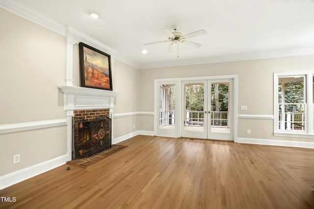 unfurnished living room featuring a lit fireplace, a healthy amount of sunlight, and wood finished floors