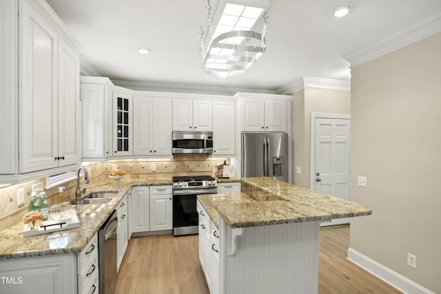 kitchen with backsplash, a kitchen island, white cabinetry, appliances with stainless steel finishes, and crown molding