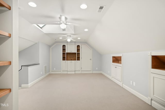 additional living space with visible vents, baseboards, vaulted ceiling with skylight, recessed lighting, and light colored carpet