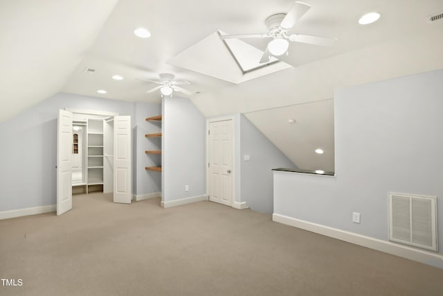 additional living space featuring visible vents, recessed lighting, vaulted ceiling with skylight, baseboards, and light colored carpet