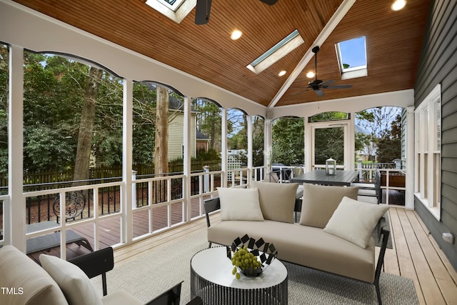 sunroom / solarium featuring vaulted ceiling with skylight, plenty of natural light, wood ceiling, and ceiling fan