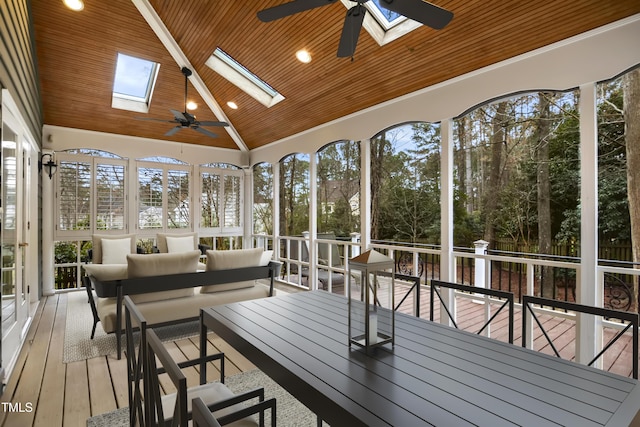 unfurnished sunroom featuring vaulted ceiling with skylight, wooden ceiling, and a ceiling fan