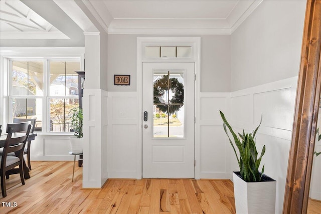 entrance foyer featuring a decorative wall, light wood-style flooring, and ornamental molding