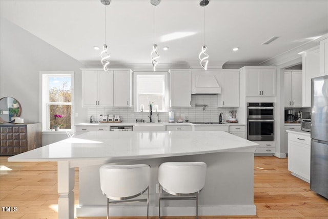 kitchen with light wood-style flooring, a sink, stainless steel appliances, white cabinetry, and tasteful backsplash