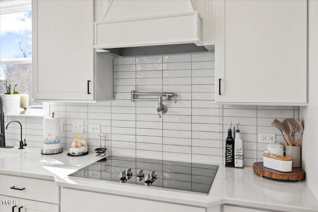 kitchen with backsplash, black electric cooktop, custom exhaust hood, and white cabinetry