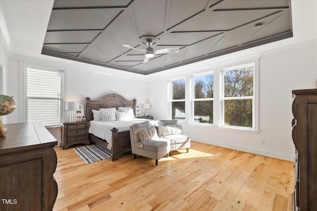 bedroom featuring coffered ceiling, baseboards, light wood finished floors, and ornamental molding