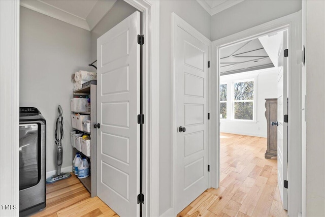 clothes washing area with light wood finished floors, laundry area, washer / dryer, and crown molding