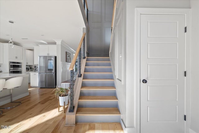 stairway featuring wood finished floors and crown molding