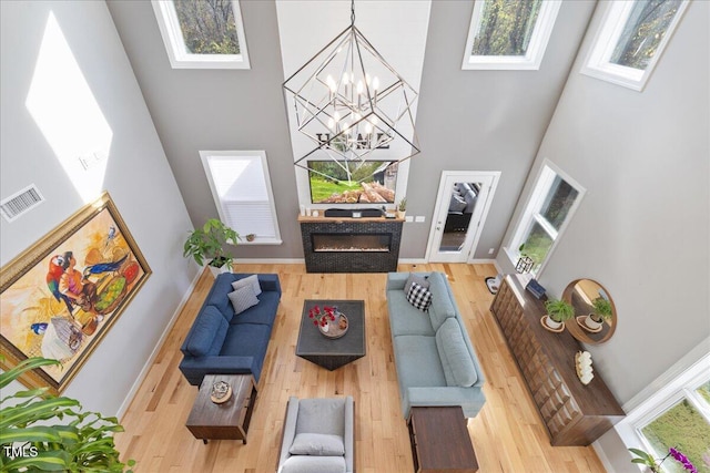 living room with a glass covered fireplace, plenty of natural light, visible vents, and a towering ceiling