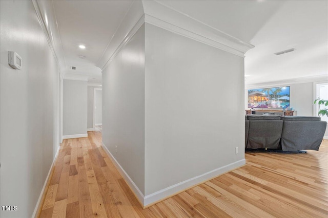 hallway with baseboards, light wood finished floors, and ornamental molding