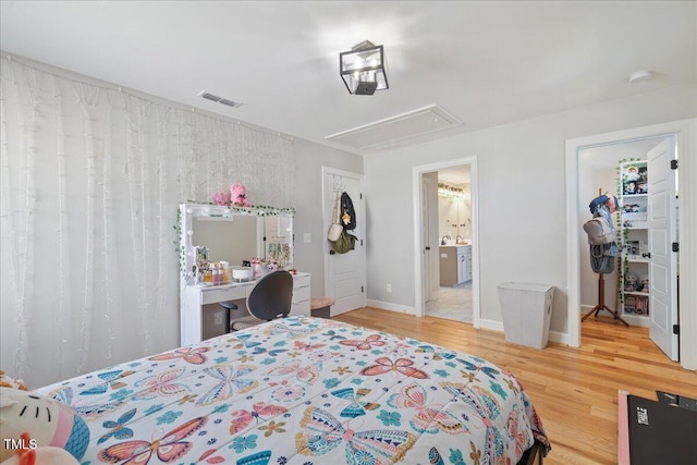 bedroom with attic access, wood finished floors, baseboards, and visible vents