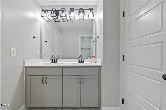 bathroom with a sink, baseboards, and double vanity