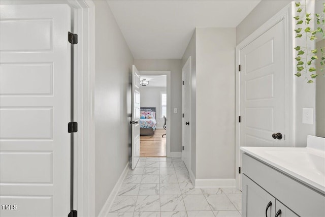 bathroom featuring marble finish floor, vanity, and baseboards