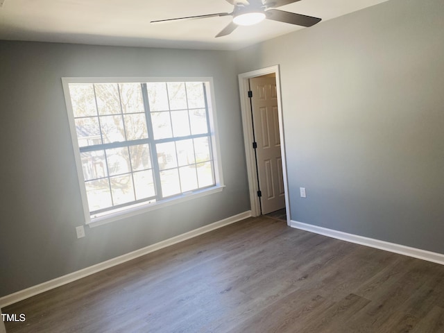 unfurnished room with a ceiling fan, baseboards, and dark wood-style flooring