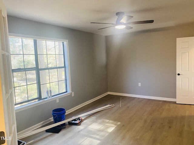 empty room featuring baseboards, a healthy amount of sunlight, wood finished floors, and a ceiling fan