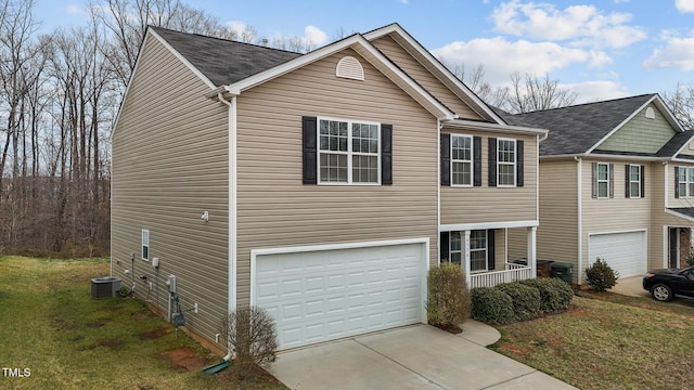 view of front of property featuring an attached garage, a front lawn, driveway, and central AC