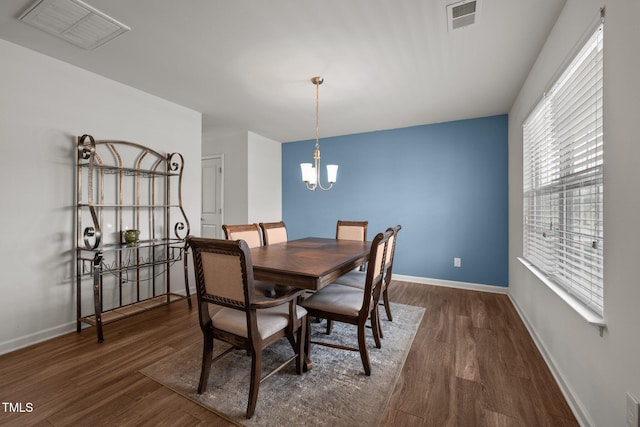 dining area with visible vents, baseboards, a notable chandelier, and wood finished floors