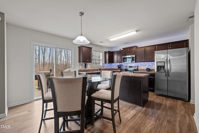 kitchen with dark brown cabinetry, tasteful backsplash, a kitchen island, and stainless steel appliances