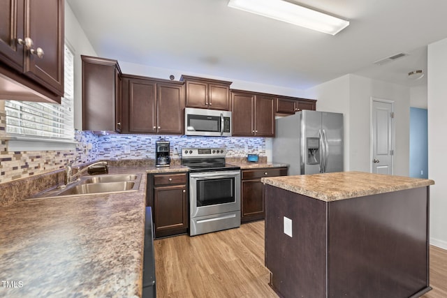 kitchen with visible vents, light wood-style flooring, a sink, stainless steel appliances, and dark brown cabinets