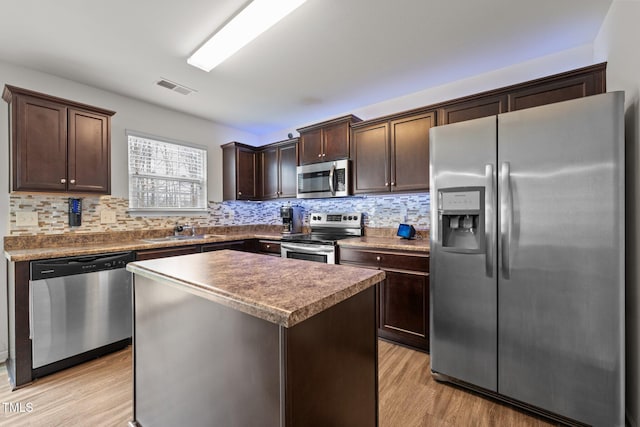 kitchen with light wood finished floors, visible vents, dark brown cabinets, appliances with stainless steel finishes, and a sink