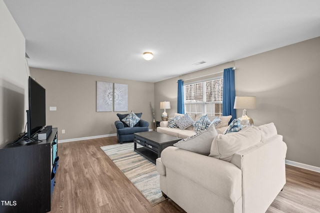 living area featuring visible vents, baseboards, and wood finished floors