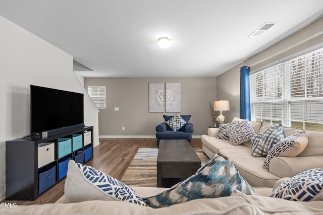 living area featuring a wealth of natural light, visible vents, baseboards, and wood finished floors