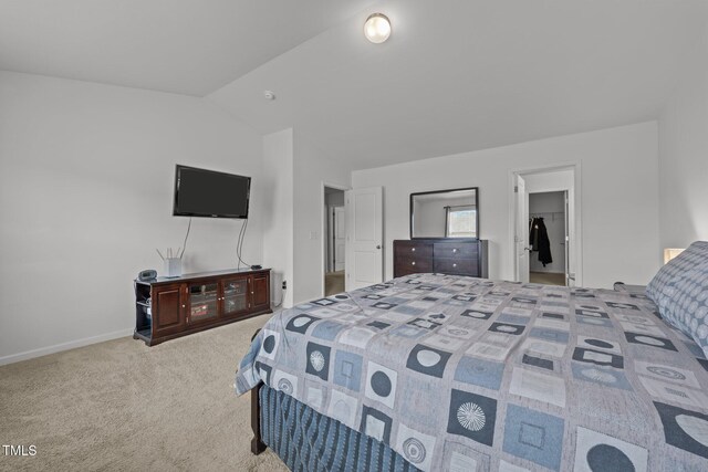 bedroom featuring a walk in closet, vaulted ceiling, and carpet floors