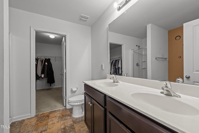 full bath featuring double vanity, toilet, a shower with door, and a sink