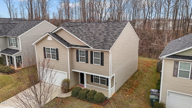 traditional home featuring an attached garage, driveway, and roof with shingles