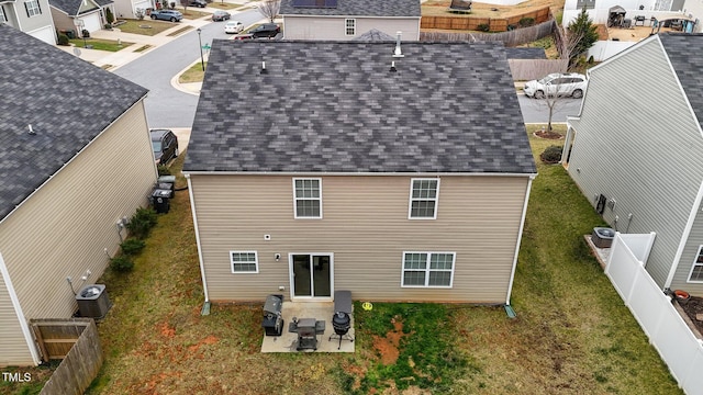 rear view of house with a yard, cooling unit, and a shingled roof