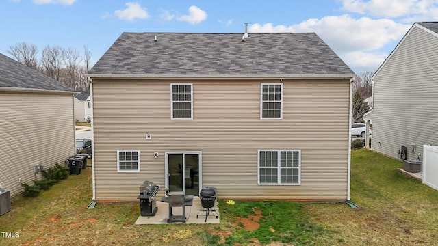 rear view of property featuring a patio area, a lawn, and roof with shingles