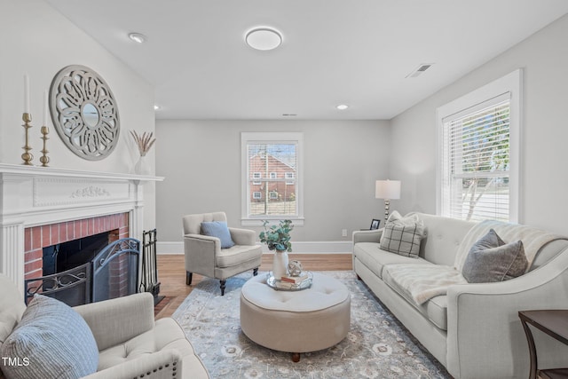 living area featuring a fireplace, wood finished floors, and a healthy amount of sunlight