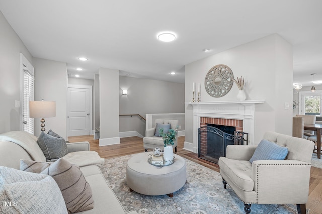 living area featuring a brick fireplace, recessed lighting, wood finished floors, and baseboards